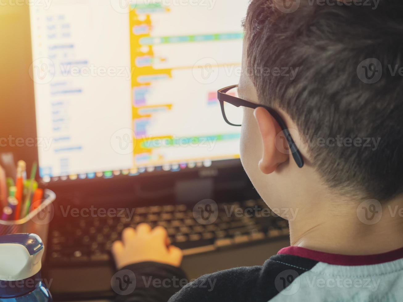 smart ung pojke arbetar på en dator för sitt nya projekt i sin datavetenskapsklass foto