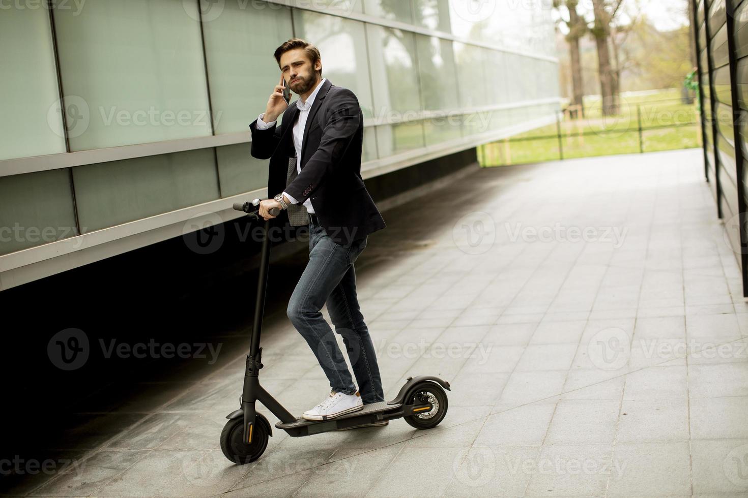 man som står på en skoter medan han pratar i en telefon foto