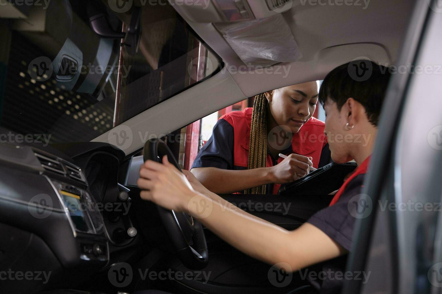 ung manlig asiatisk bil- mekaniker tekniker och partner kontroll underhåll lista med läsplatta i bil interiör på garage. fordon service fixera och reparera Arbetar, industriell ockupation företag jobb. foto