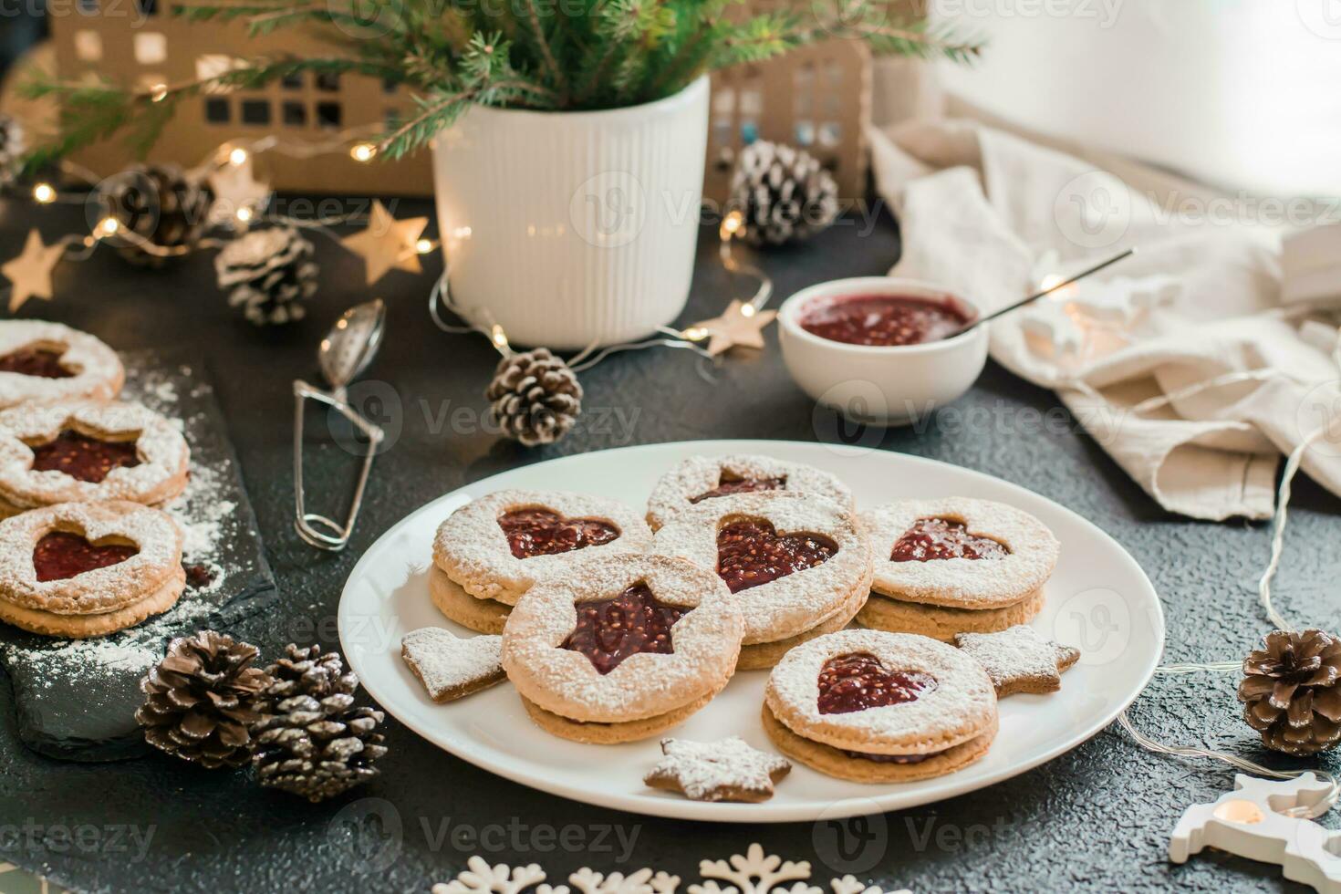 redo linzer småkakor med bär sylt på en tallrik och jul dekorationer på en mörk bakgrund. matlagning jul godsaker. livsstil foto