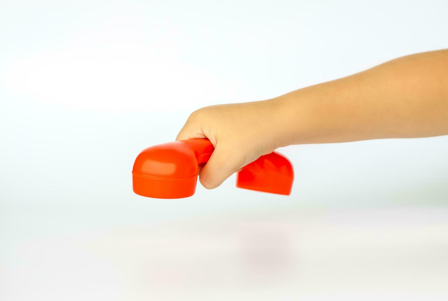 röd leksak telefon i de barnets hand. närbild av en barnets hand. isolerat på en vit bakgrund. de begrepp av ett reklam baner. foto