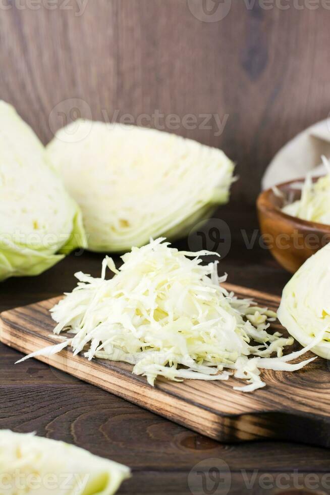 färsk rå kål skära in i remsor på en skärande styrelse på en trä- tabell. vegetarian diet. vertikal se. närbild foto