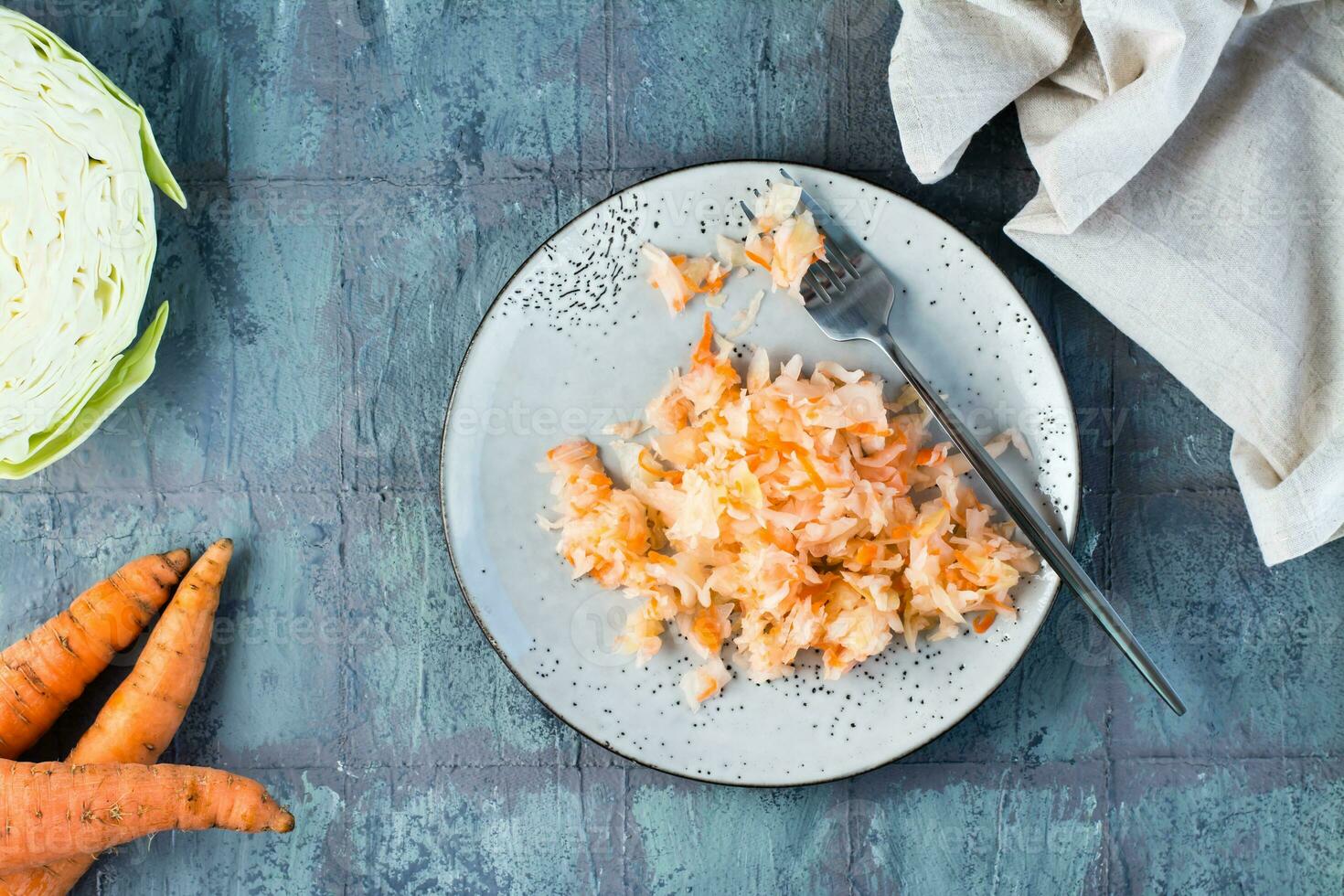 färsk surkål med morötter och en gaffel på en tallrik på de tabell. jäsning och en vegetarian diet. topp se. foto