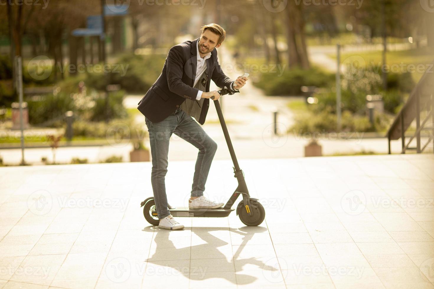 man lutar sig på en skoter och pratar i telefon foto