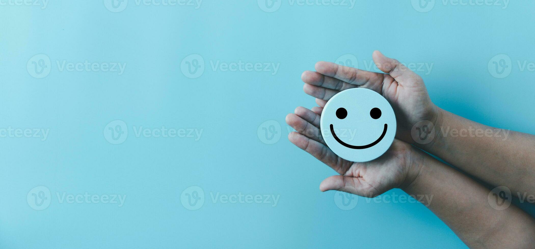 kvinna hand innehav Lycklig ansikte leende ansikte ikon på runda blå objekt. kund erfarenhet och service med tillfredsställelse begrepp. positiv tänkande, mental hälsa bedömning, värld mental hälsa dag. foto