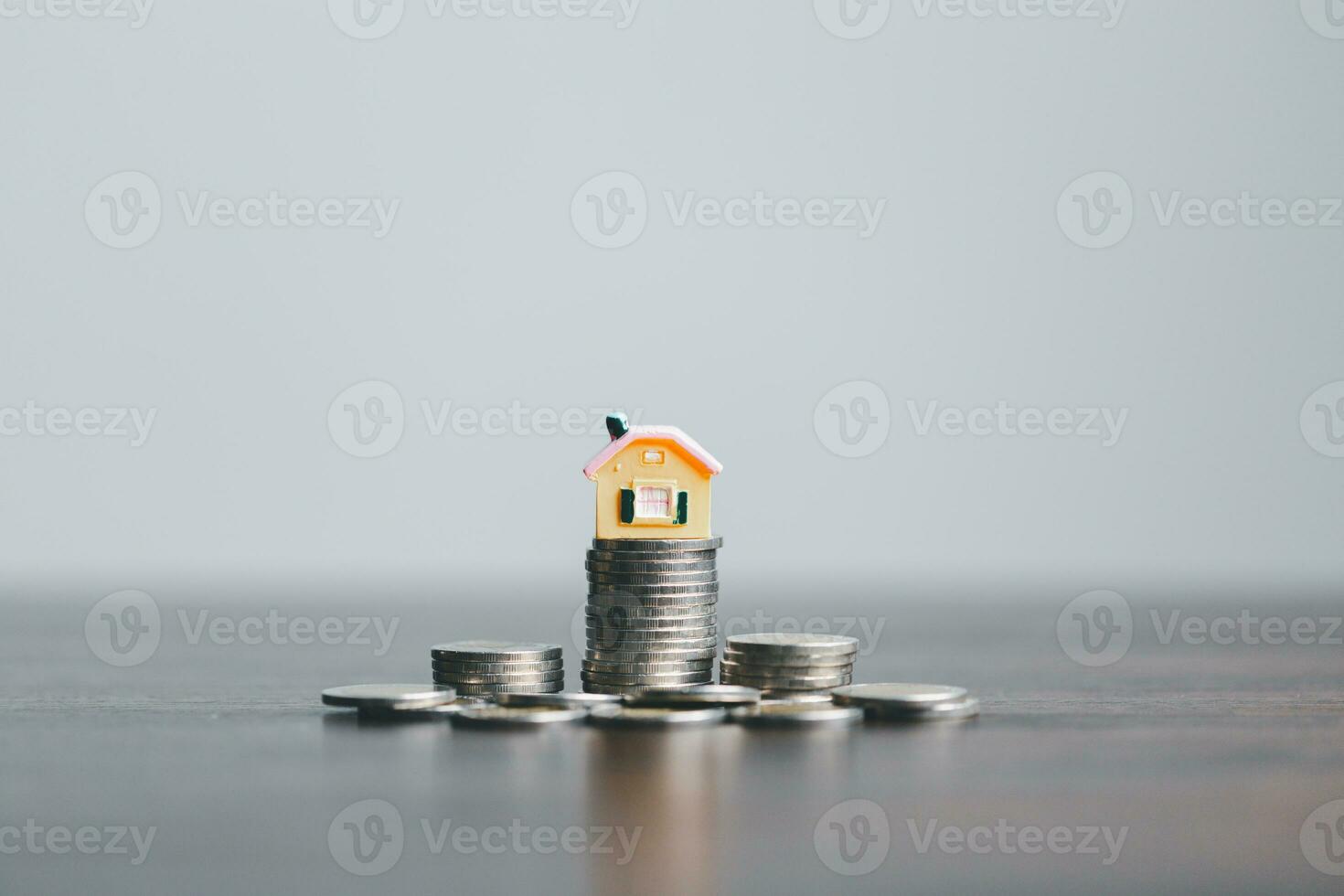 mynt stack med mini hus på trä- tabell, Hem lån, spara pengar begrepp, fast egendom investering, hus lån, omvänd inteckning, guld mynt pengar stack tillväxt, sparande pengar mynt stack framtida för Hem. foto