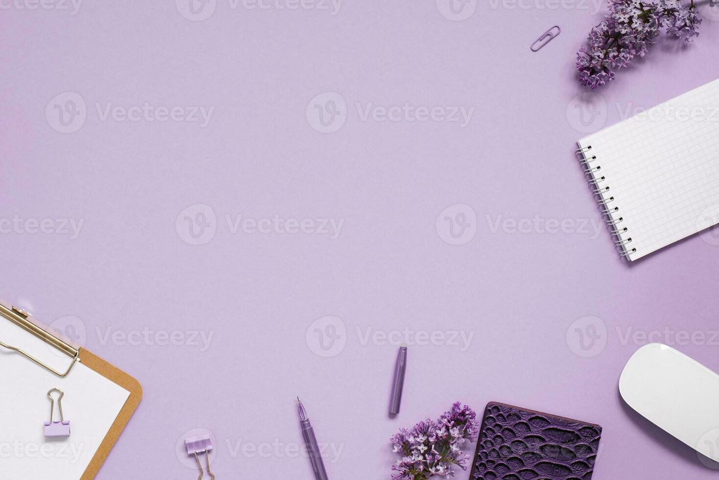 kvinnors skrivbordet närbild, tangentbord, bärbara datorer med penna, lila blommor. minimal beskurna platt sammansättning på en rosa bakgrund. kopia Plats foto