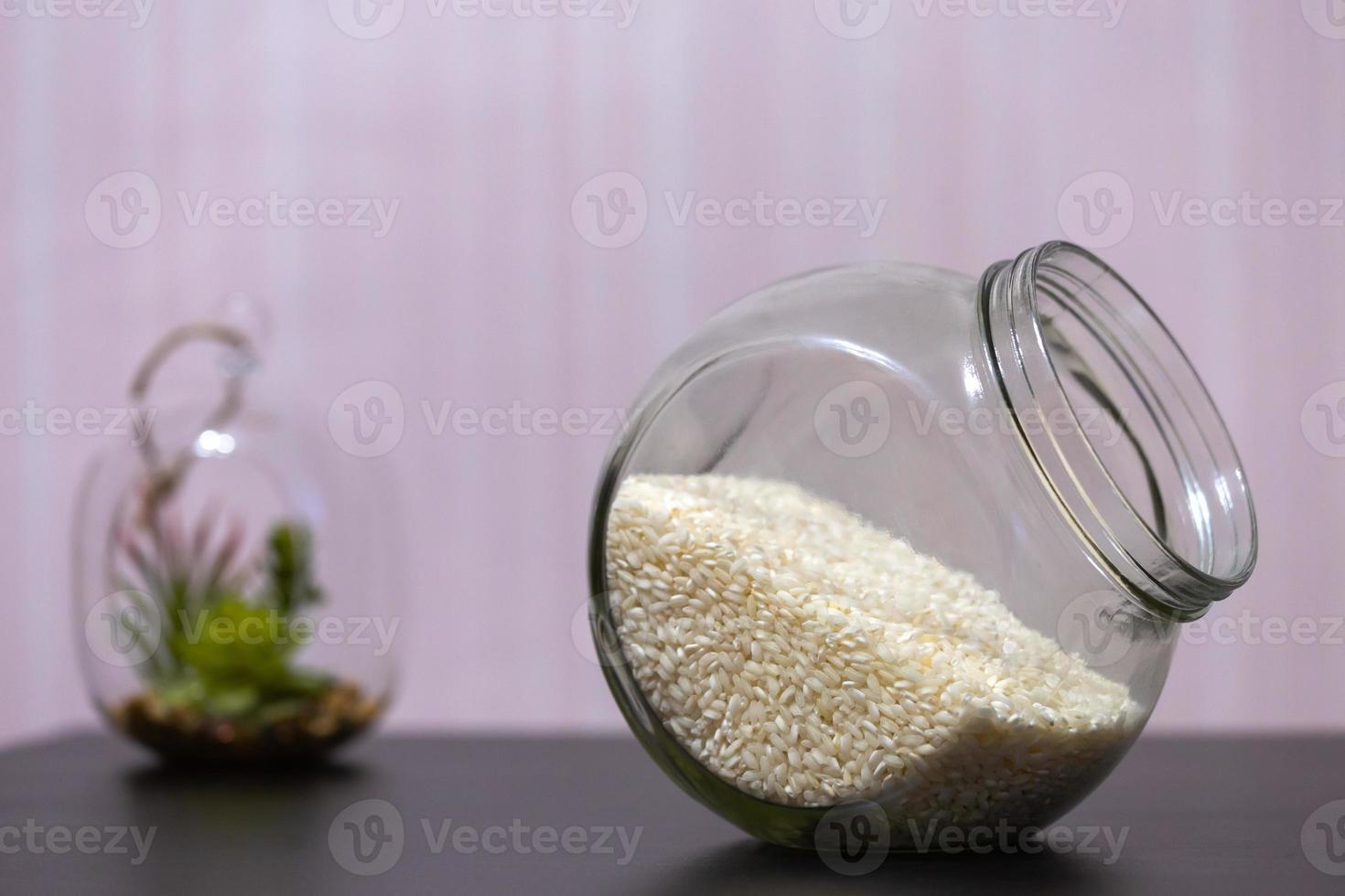 ris i en glasburk som står på ett bord med en grön växt i bakgrunden foto