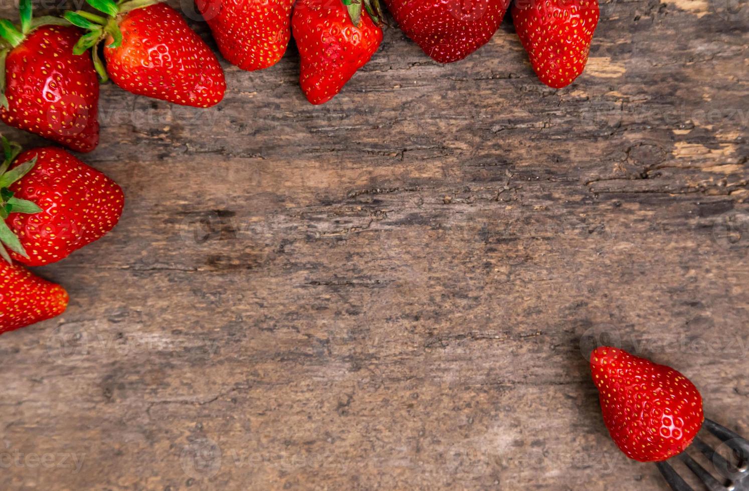 färska jordgubbar och ett bär på gaffelstilleben på mörk träbakgrund foto