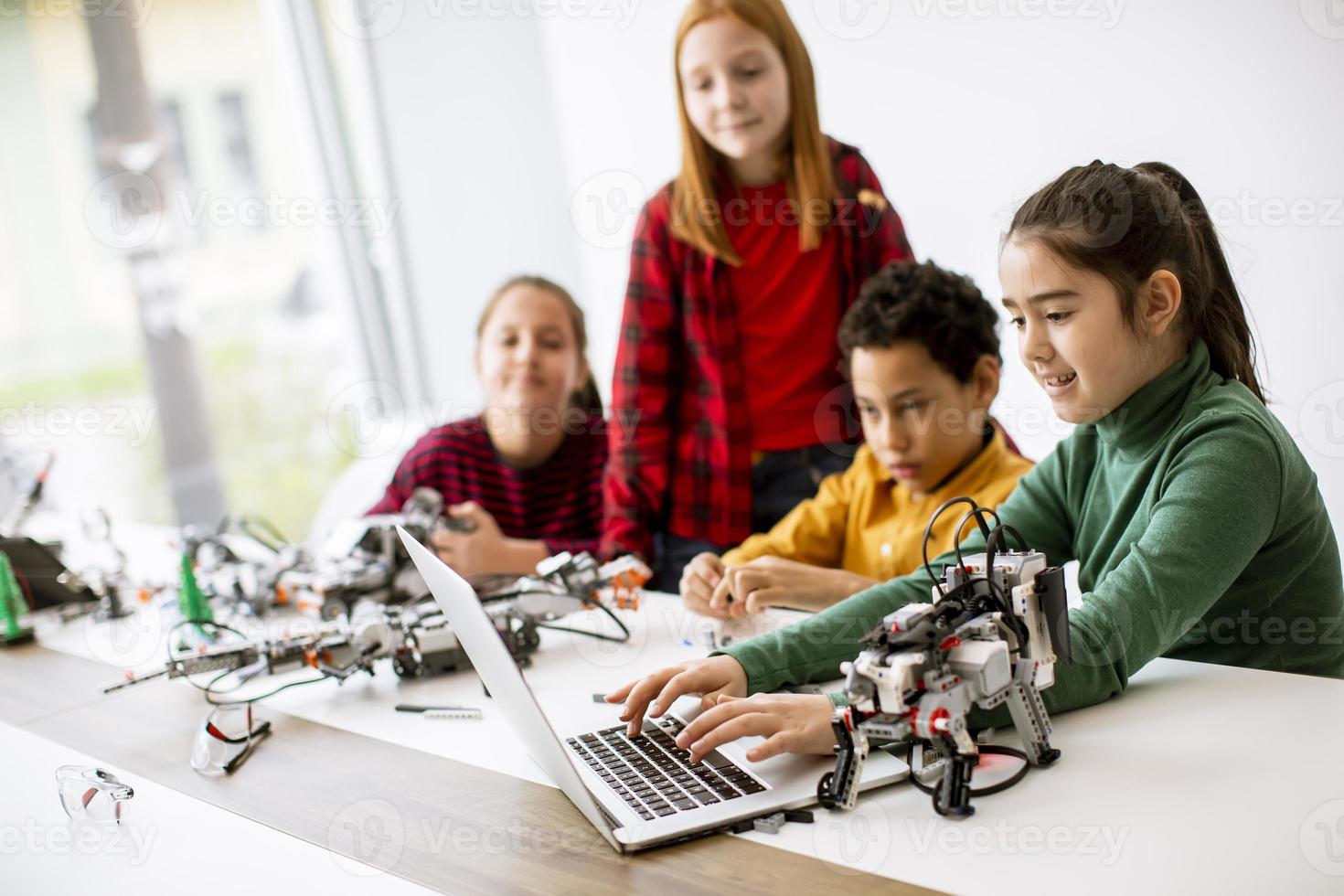 glada barn som programmerar elektriska leksaker och robotar i klassrummet för robotik foto