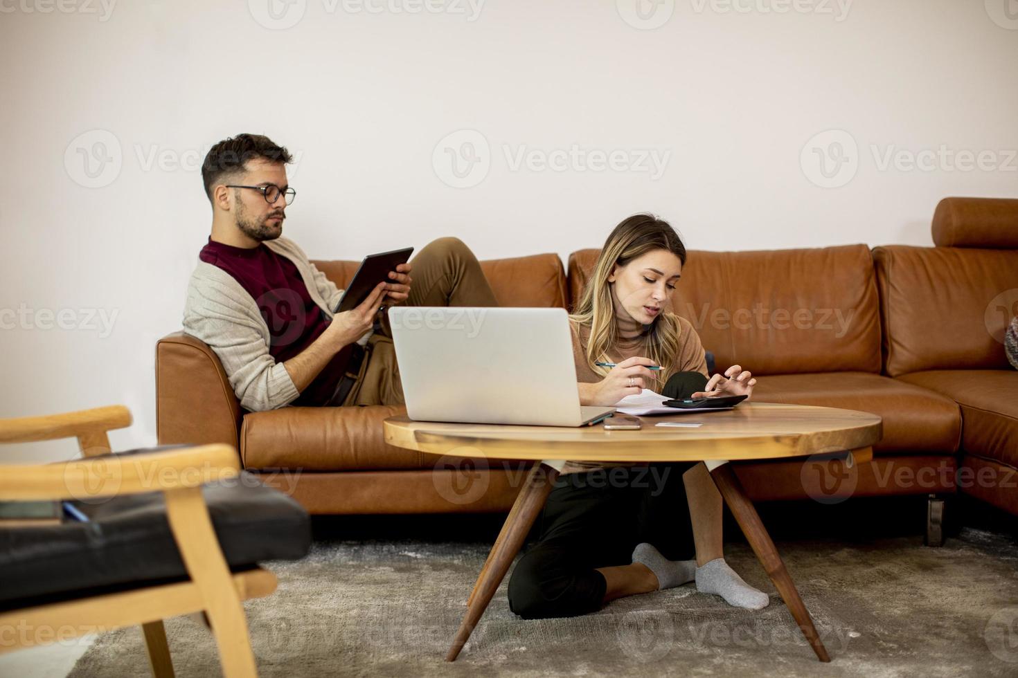 ung kvinna och ung man som använder bärbara datorn medan du sitter hemma i soffan foto