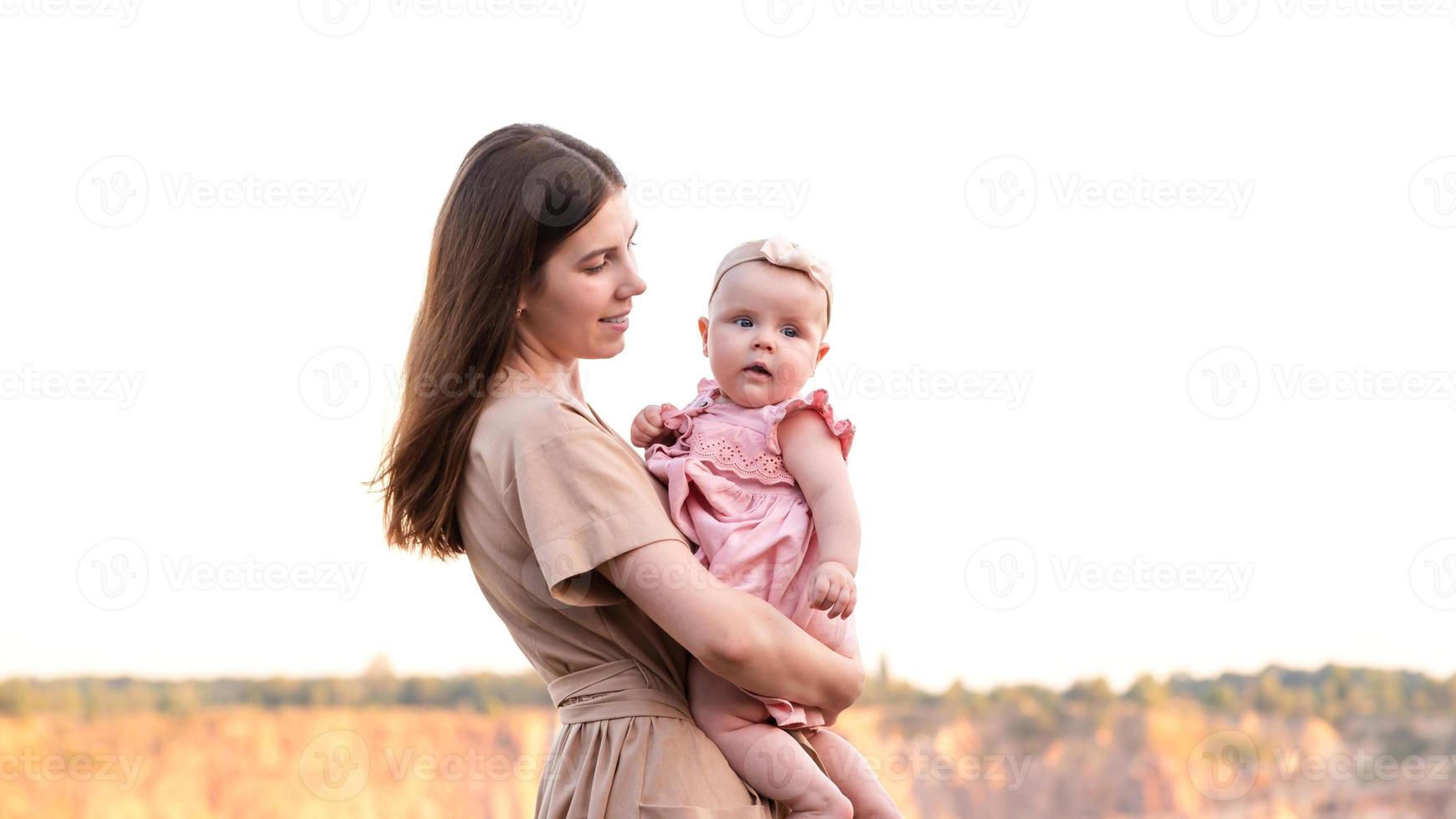 glad ung mamma håller sin unga baby dotter i armarna foto