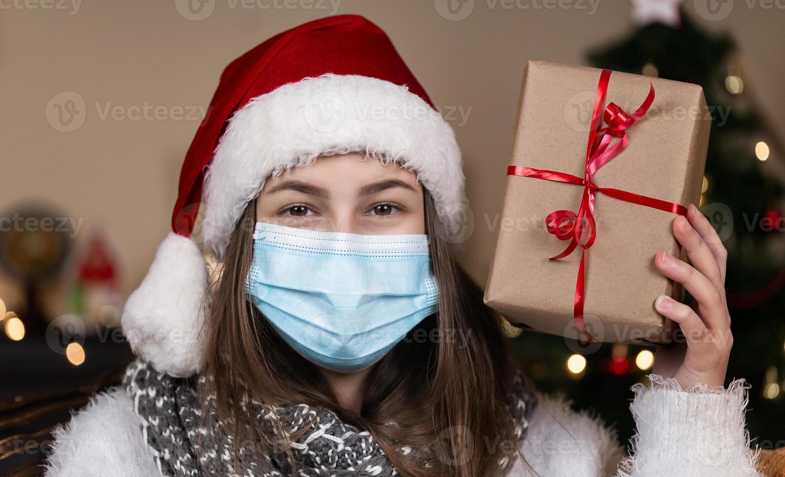 porträtt av en kvinna som bär santa hatt och vit tröja i medicinsk mask foto