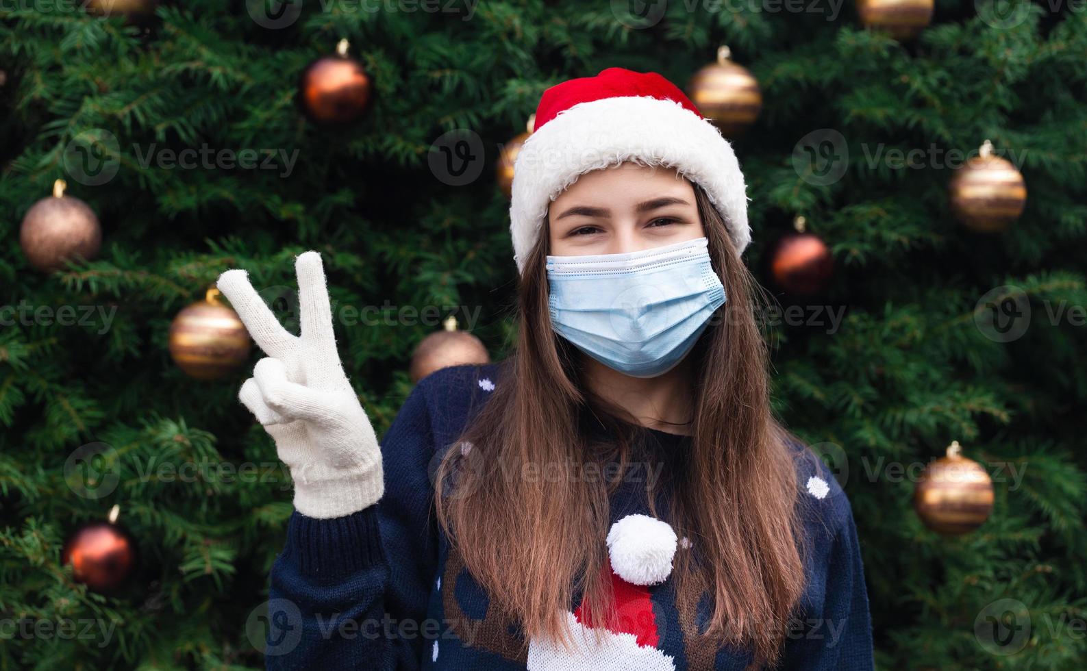 närbild porträtt av kvinna som bär en jultomten hatt och medicinsk mask med känslor foto