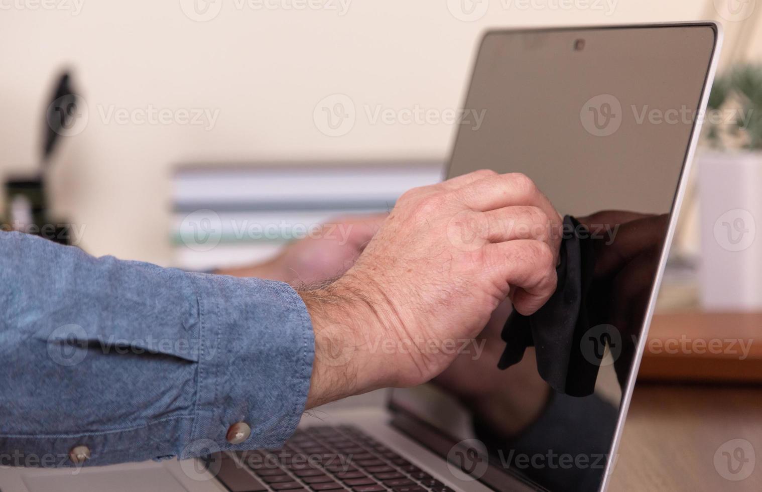 manhänder som rengör bärbar datorskärm med trasa foto