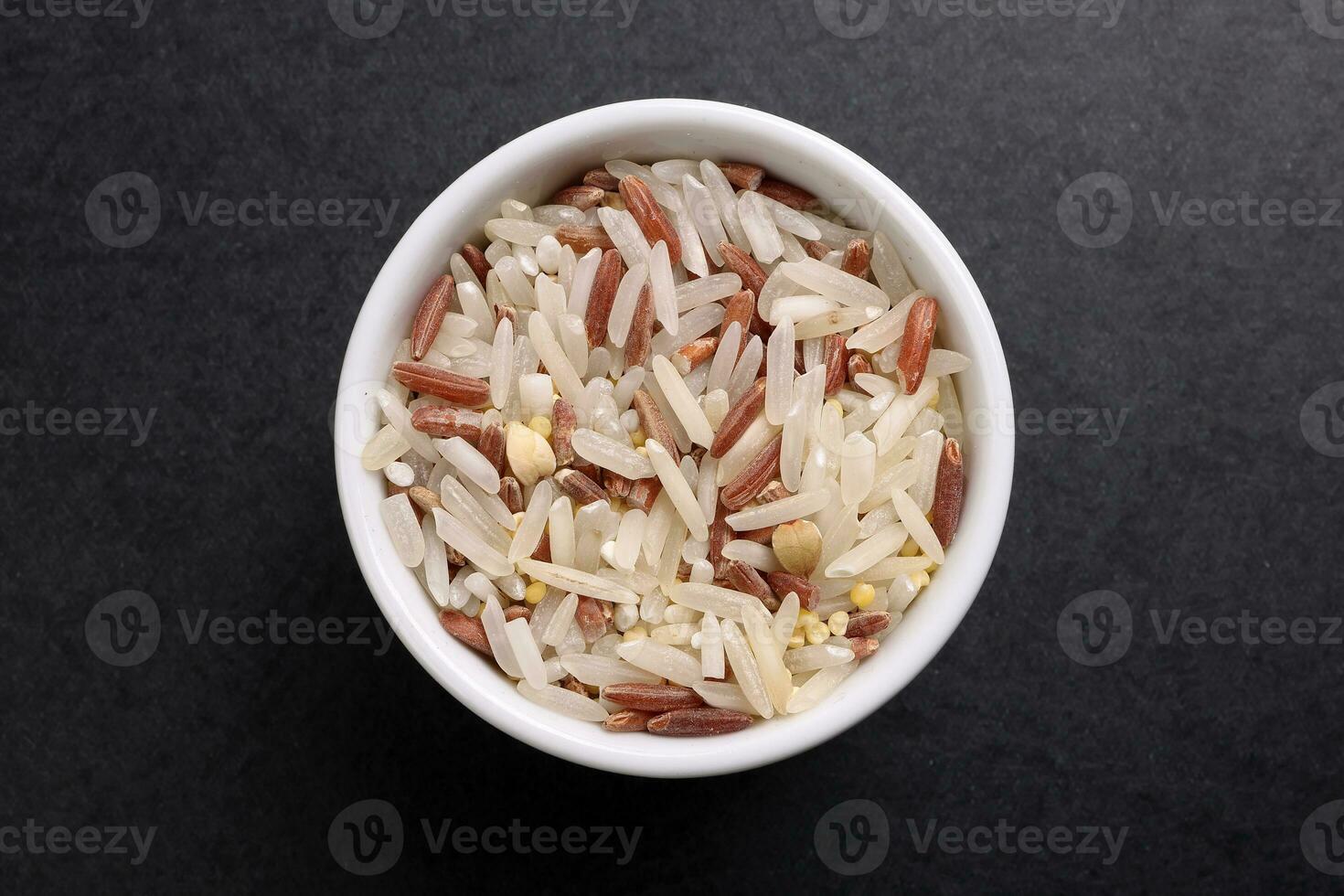 blandad låg glykemiskt index friska ris spannmål basmati hirs bovete röd ris i små vit keramisk skål över svart bakgrund foto