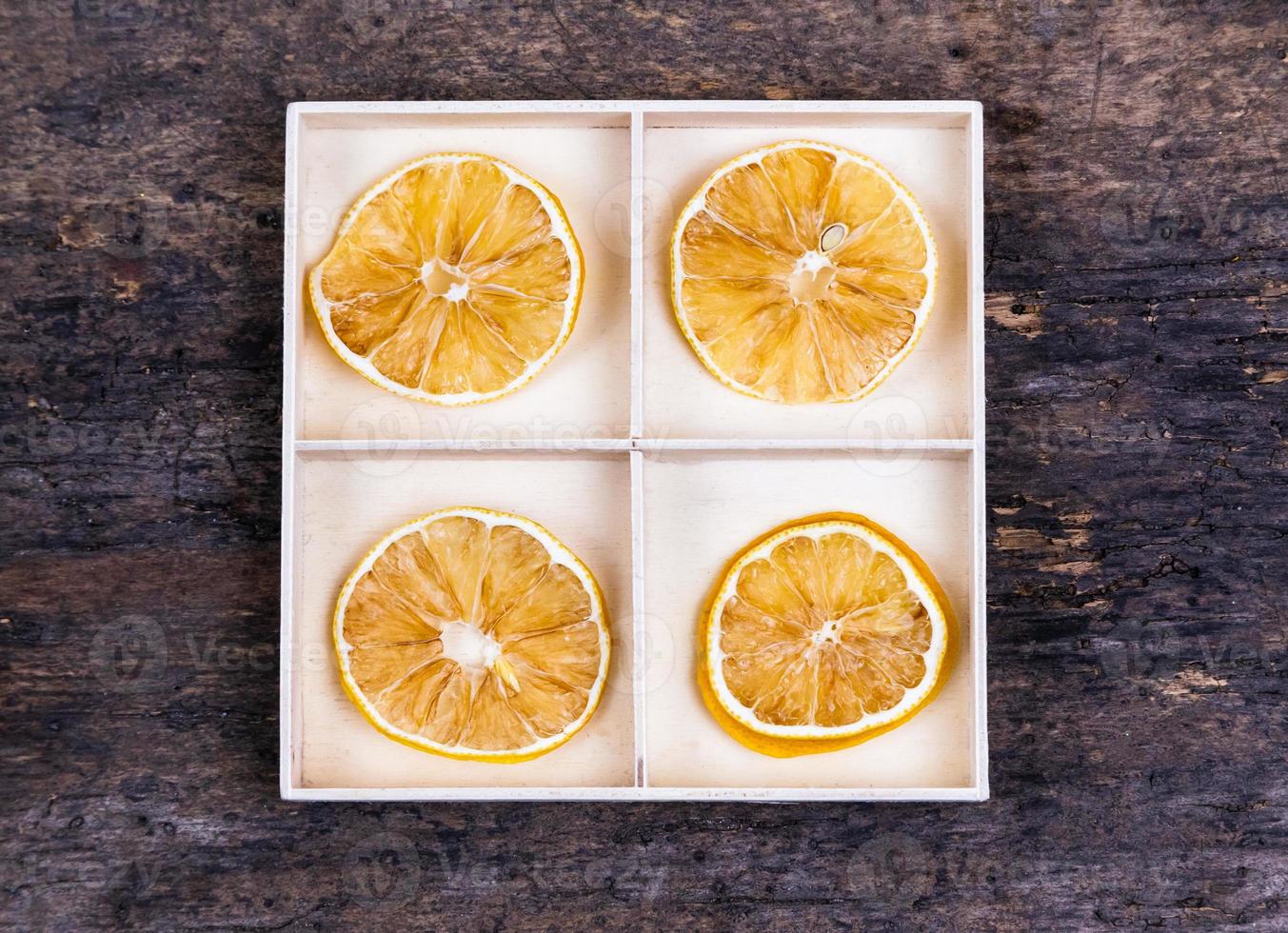 en vit låda med fack på en träbakgrund fylld med torkade apelsiner foto