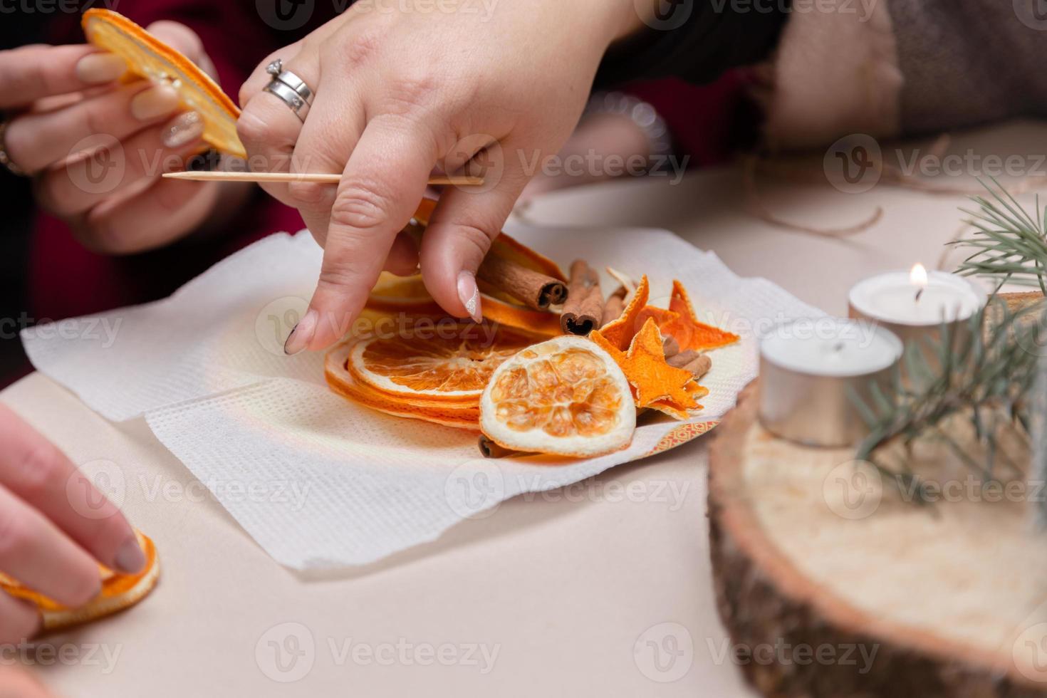 kvinnor hand gör dekorationer från torkade apelsiner foto