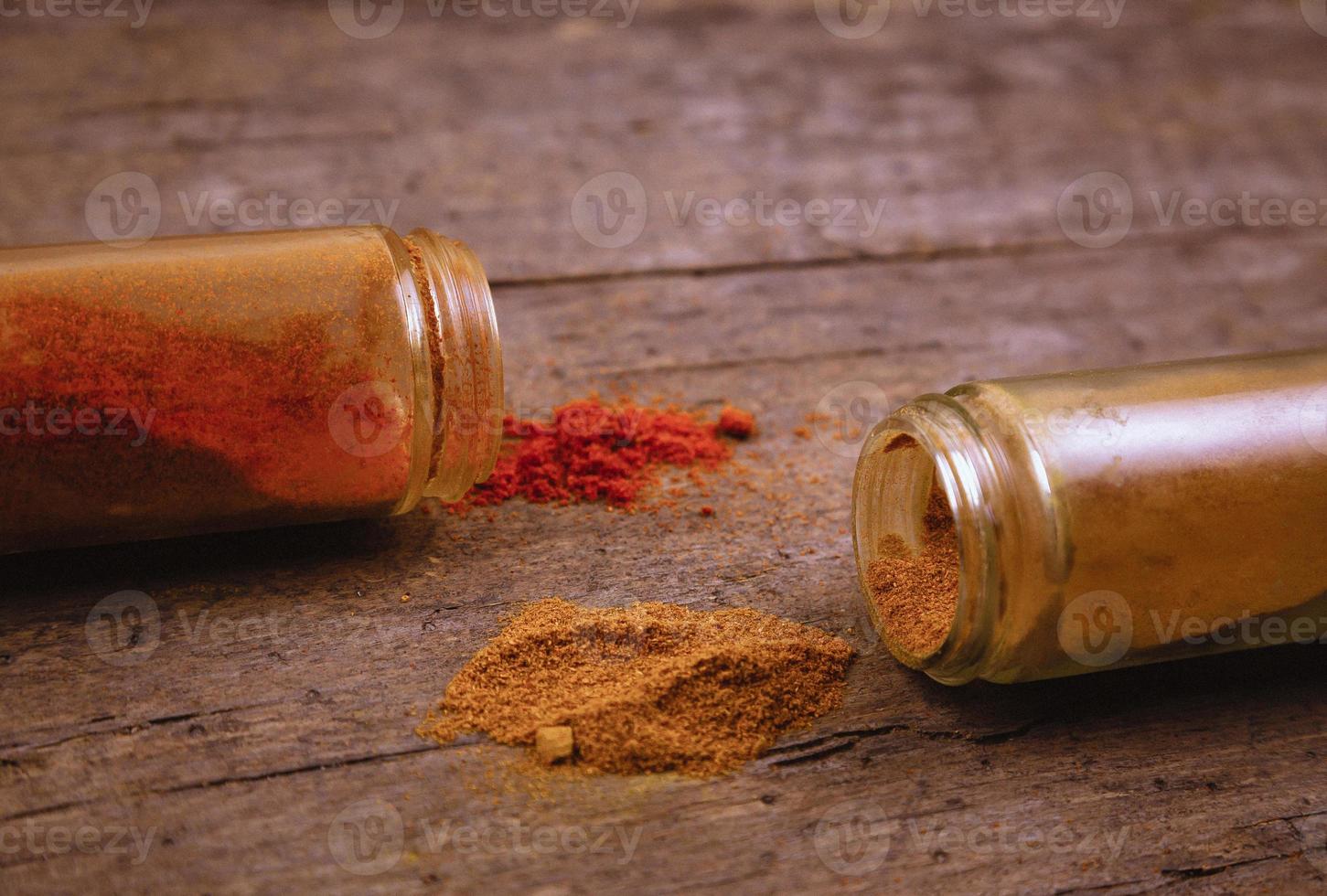 chili färgglada pulver kryddor utspridda från flaskan på trä bakgrund foto