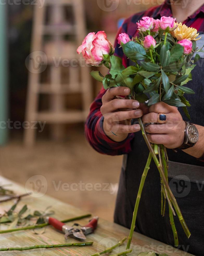 blomsterhandlare man gör blombukett i affären foto