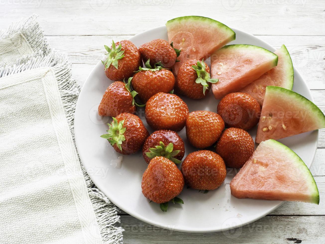 röda mogna jordgubbar och saftiga vattenmelonskivor på en platta ovanifrån foto