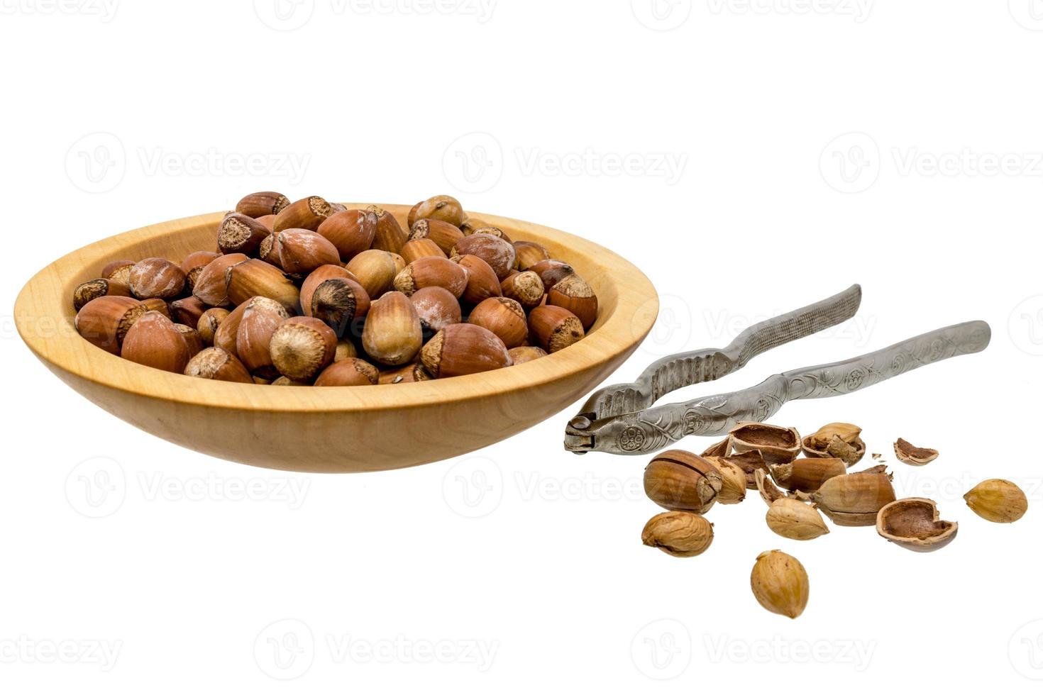träskål med hasselnötter nötknäpparen och öppnade nötter som isoleras på vitt foto