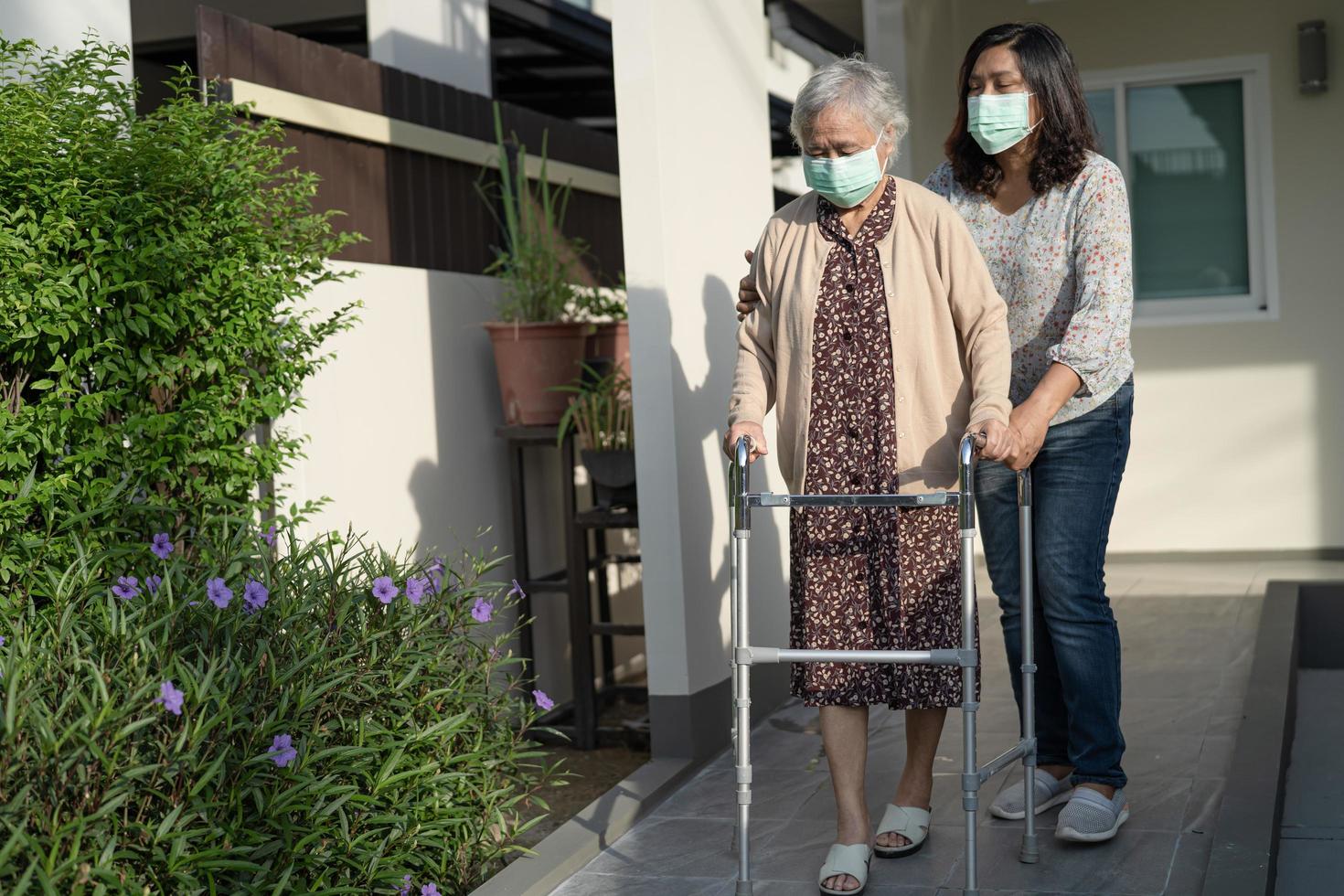 asiatisk senior eller äldre gammal damkvinna går med rullator och bär en ansiktsmask för att skydda säkerhetsinfektion covid 19 coronavirus foto