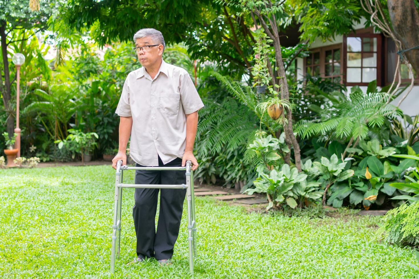 glad gammal äldre asiatisk man använder en rollator och går på bakgården. begreppet lycklig pensionering med omsorg från en vårdgivare och sparande och senior sjukförsäkring foto