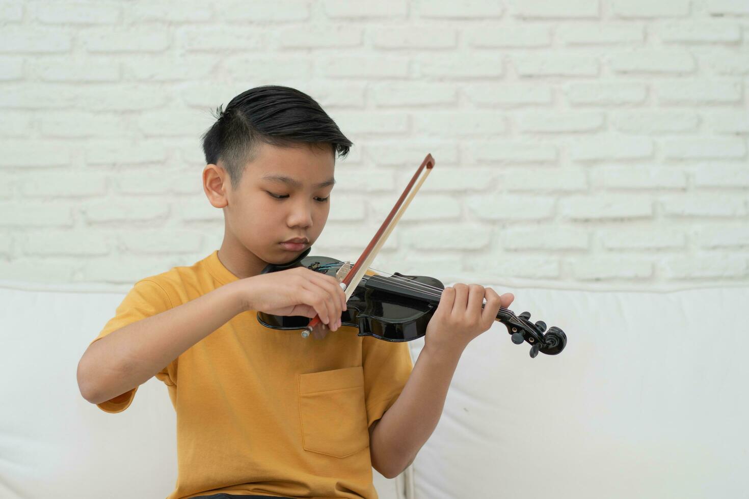 ett litet asiatiskt barn som spelar och tränar violinmusikaliskt stränginstrument mot i hemmet, koncept för musikalisk utbildning, inspiration, tonåring konstskola student. foto