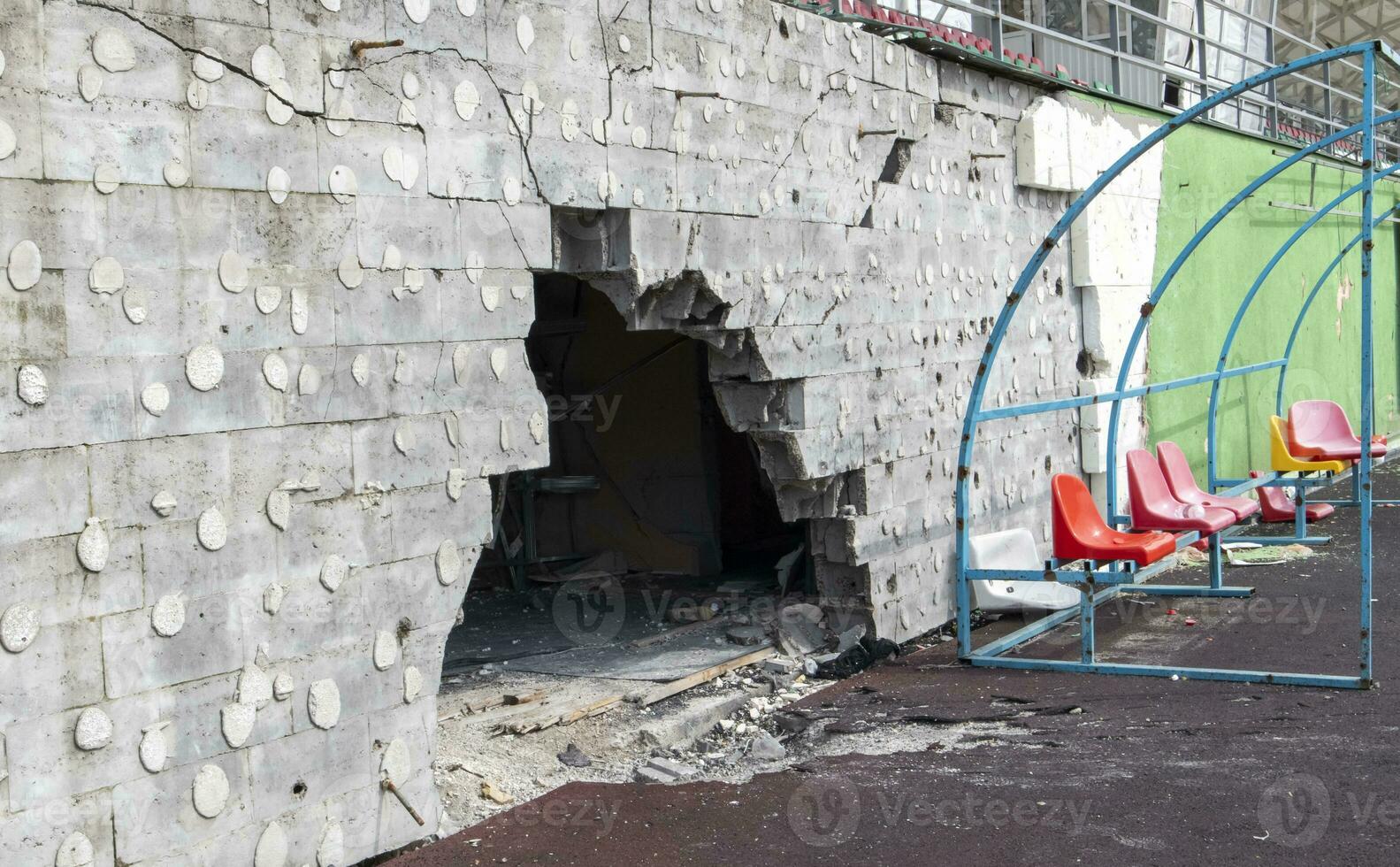 krig i ukraina. bruten plast bänkar för fläktar på de podium, i en förstörd fotboll stadion i en barns fotboll skola. de konsekvenser av beskjutningen från artilleri. foto