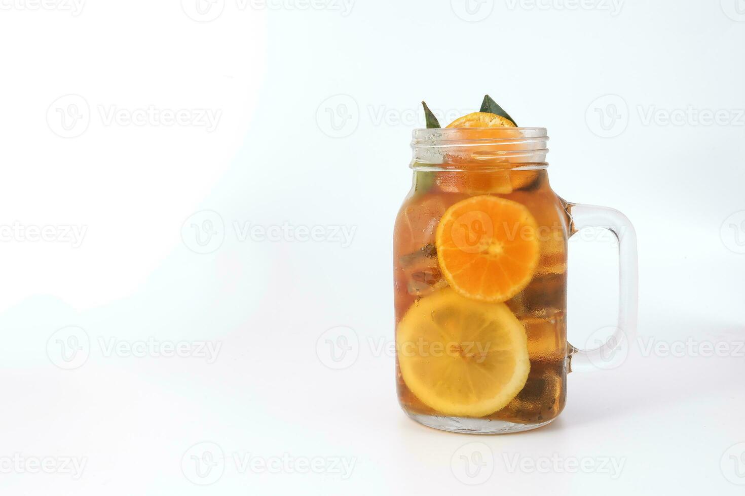 flytande is citron- orange te med skiva grön blad kanel pinne i transparent glas burk råna på vit bakgrund foto