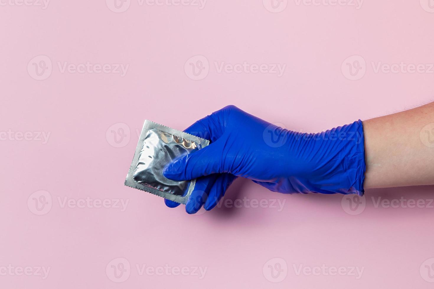 en hand i en blå latexhandske håller kondom foto
