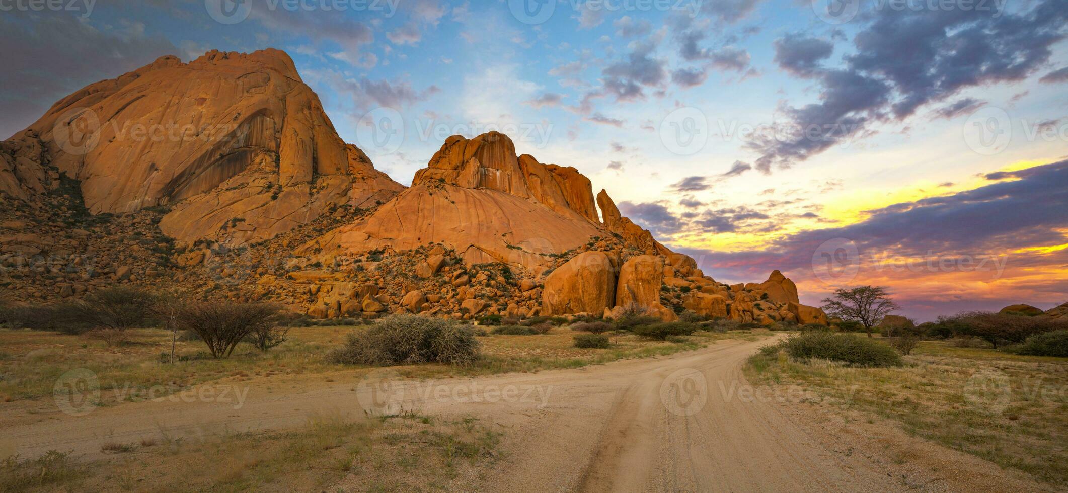 granit stenar av Spitzkoppe med gul och blå moln på solnedgång foto