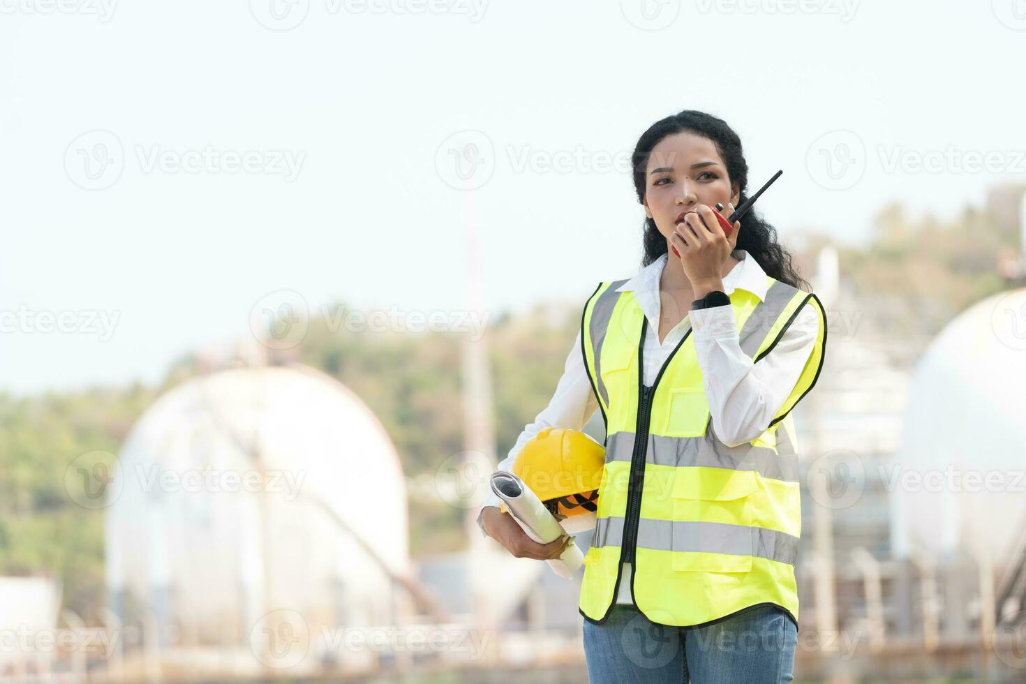 kvinna ingenjör med Hardhat med petrokemiska fabrik bakgrund. asiatisk kvinna innehav läsplatta, planen och walkie talkie. foto