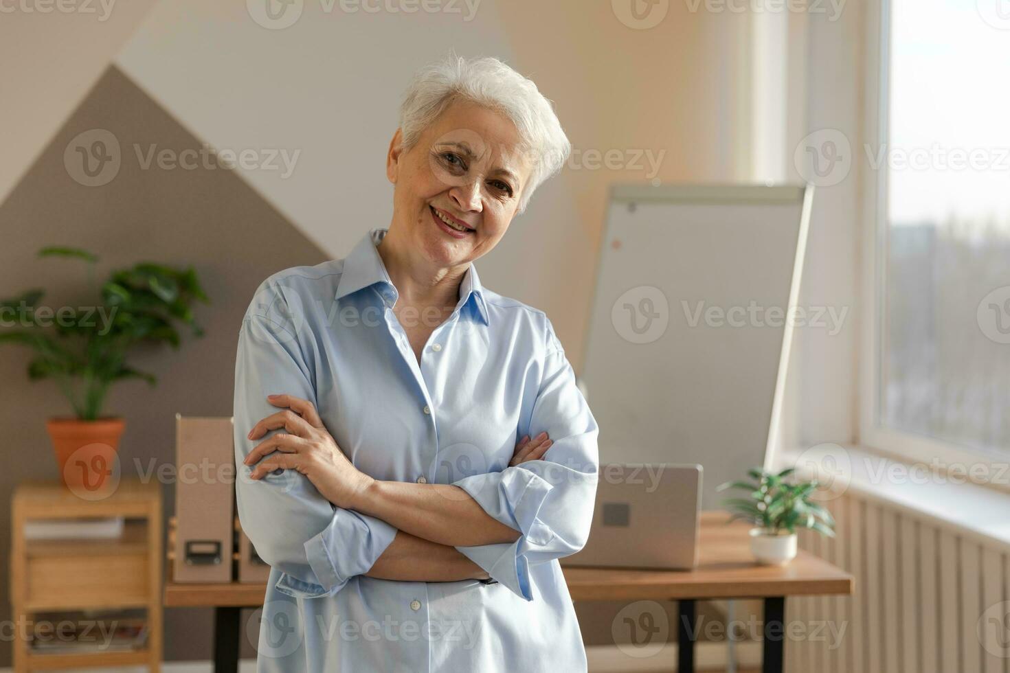 porträtt av självsäker eleganta europeisk mitten åldrig senior kvinna på arbetsplats. eleganta äldre mogna 60s grå håriga lady affärskvinna i modern kontor. chef ledare lärare professionell arbetstagare. foto