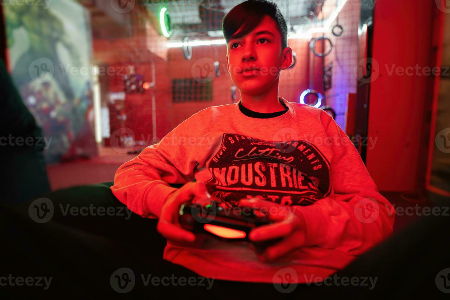 tonåring pojke gamer spela gamepad video spel trösta i röd gaming rum. foto