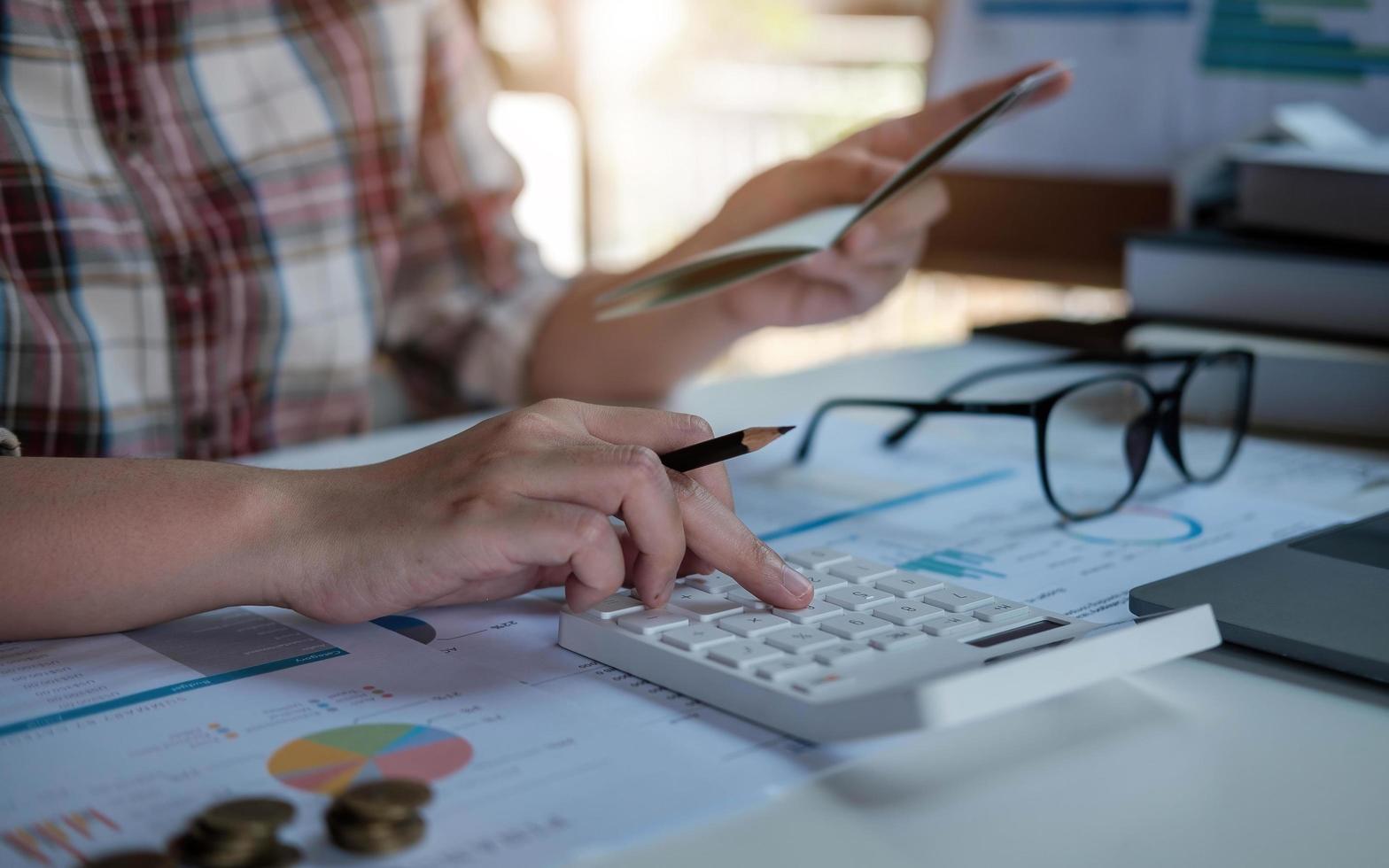 finansiell data som analyserar handskrivning och räknar med miniräknare i office på träskrivbord foto