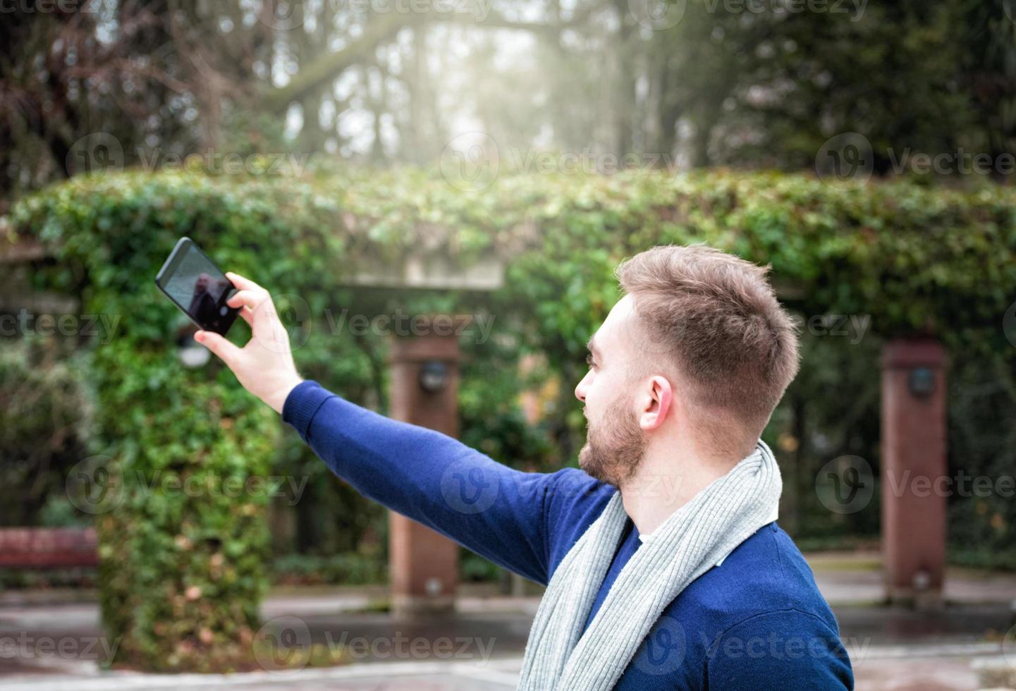 ung man med ryggen mot kameran tar en bild med sin mobiltelefon foto