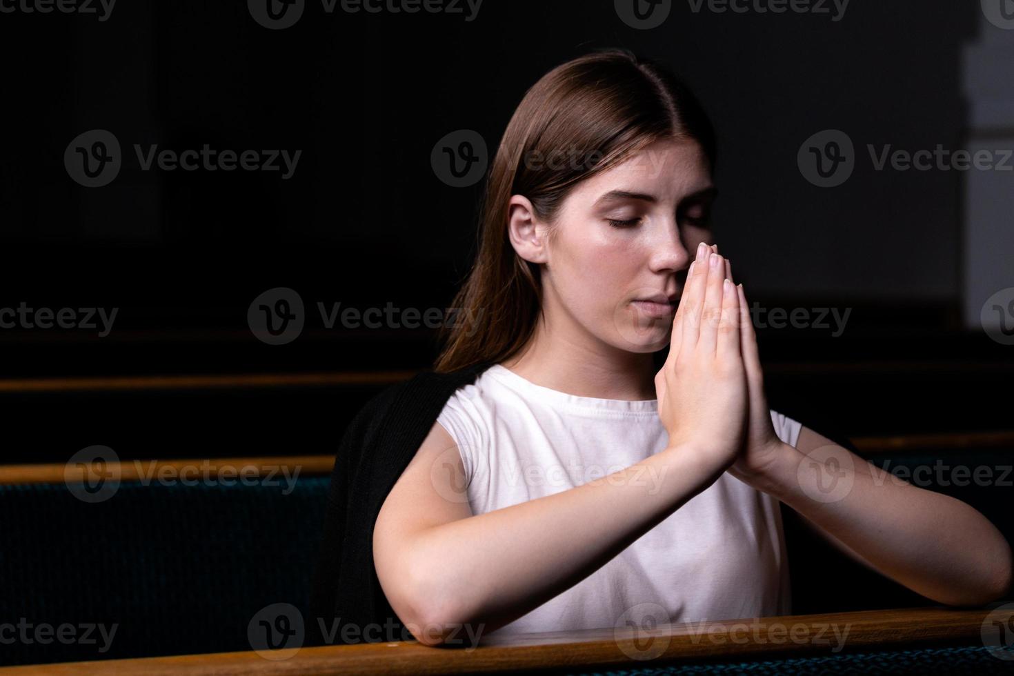 en kristen flicka i vit skjorta ber med ödmjukt hjärta i kyrkan foto