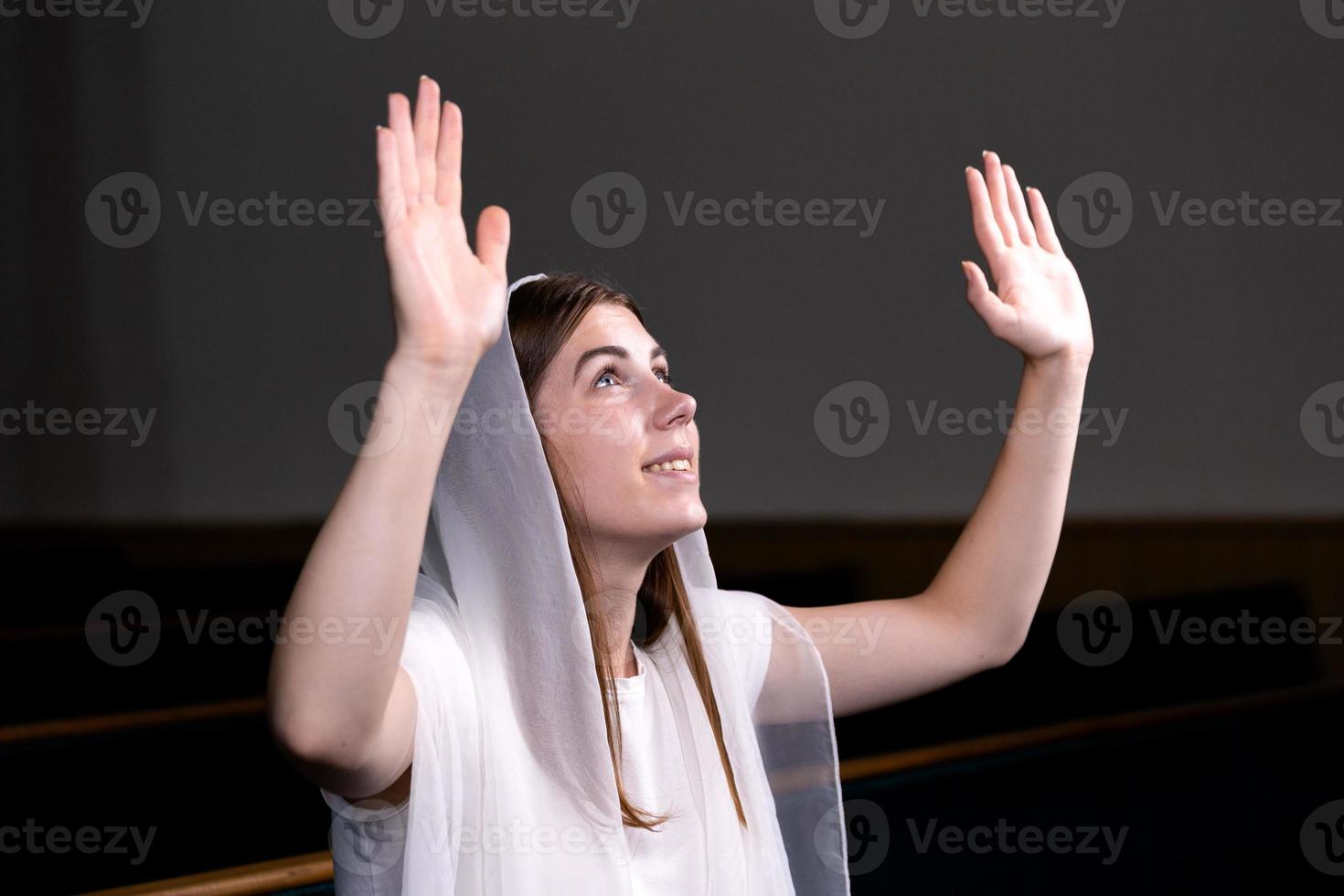 en ung blygsam tjej med en näsduk på huvudet sitter i kyrkan och ber foto