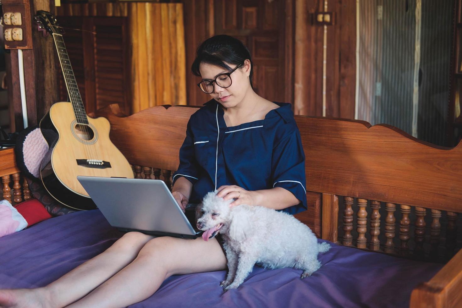 ung kvinna som arbetar på bärbara datorn hemma söt liten hund förutom att arbeta hemifrån foto