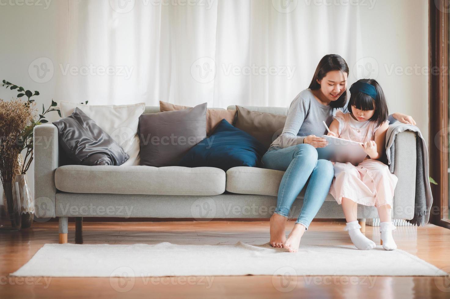 glad asiatisk familj mor och dotter studera tillsammans foto