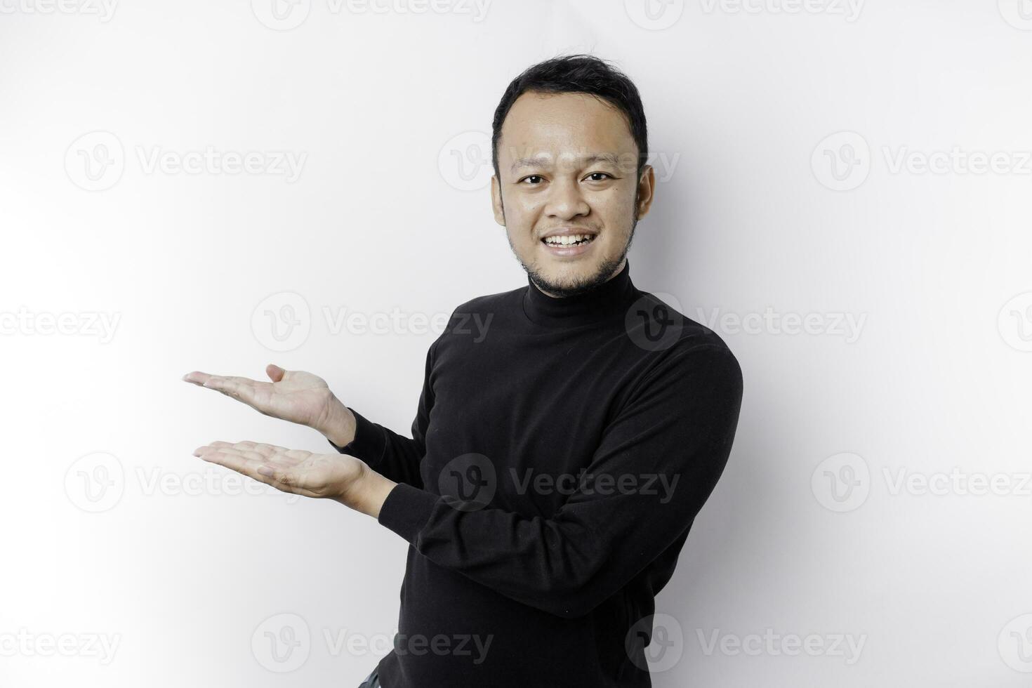 upphetsad asiatisk man bär svart skjorta pekande på de kopia Plats bredvid honom, isolerat förbi vit bakgrund foto