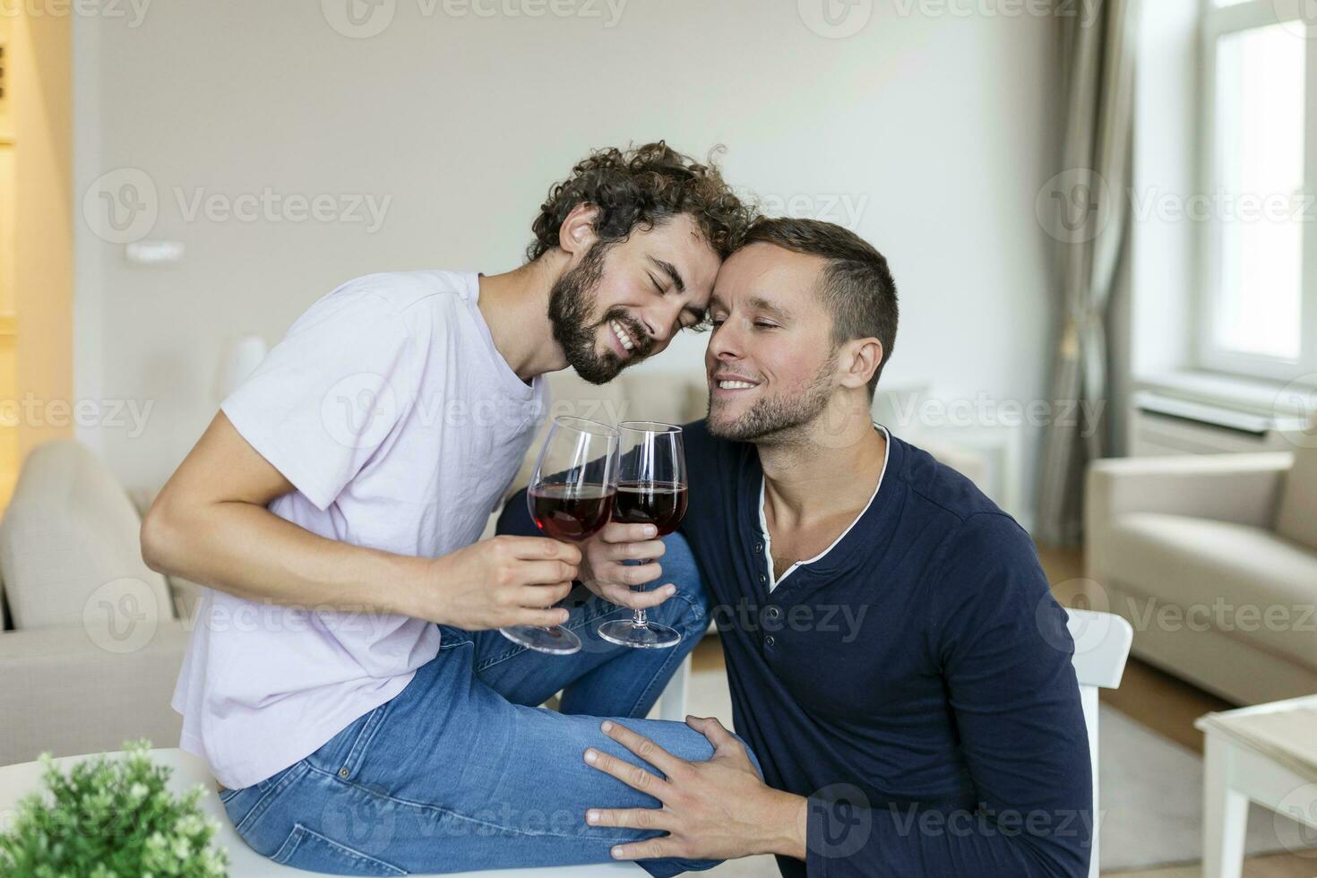 lgbtq par fattande varje Övrig och sjunker vin inomhus. två romantisk ung manlig älskande ser på varje Övrig medan Sammanträde tillsammans i deras levande rum. ung Gay par varelse romantisk på Hem. foto