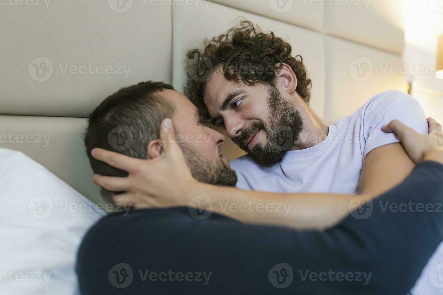 stilig Gay par liggande i säng tillsammans. romantisk ung Gay par fattande varje Övrig kärleksfullt i deras sovrum. två glad ung manlig älskande bindning förtjust på Hem. foto
