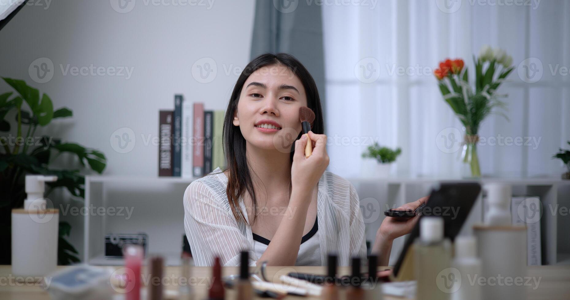 skön ung asiatisk kvinna bloggare visar på vilket sätt till göra upp och använda sig av kosmetika foto