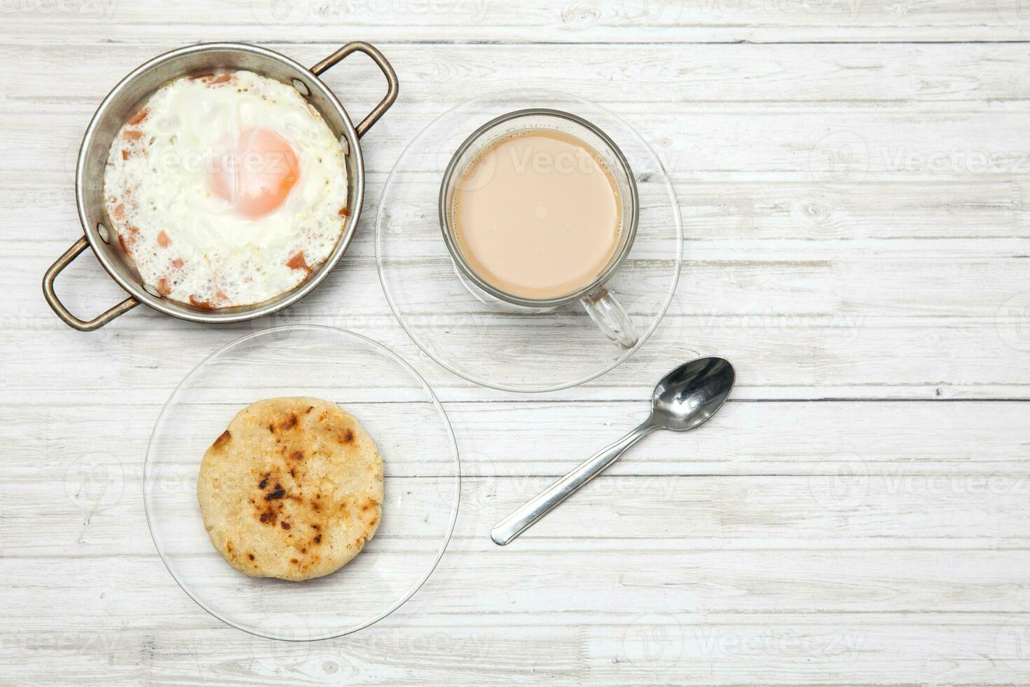 friterad ägg, kaffe och arepa på trä- vit tabell foto