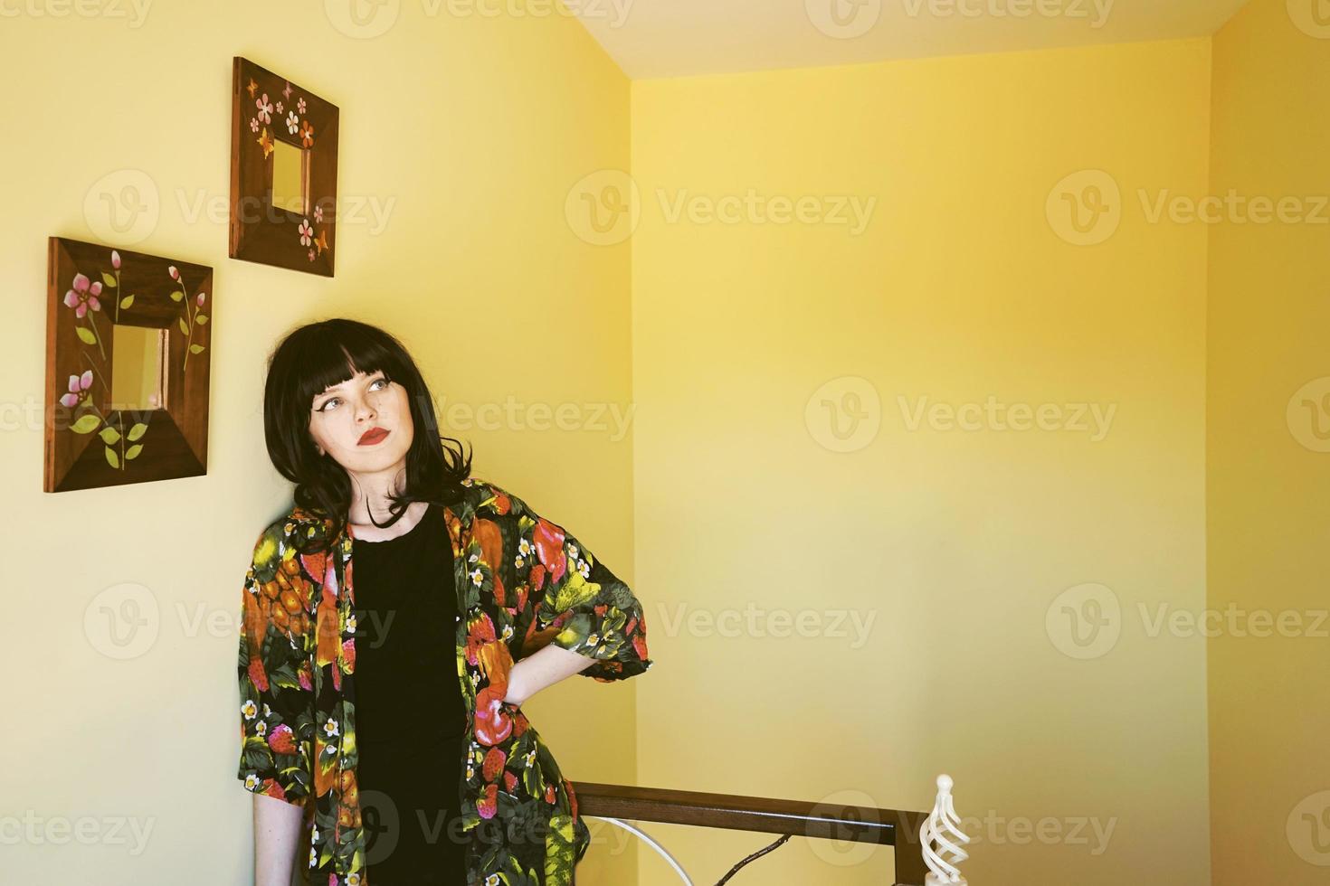 vacker brunett kvinna i ett gult rum i hennes hem foto