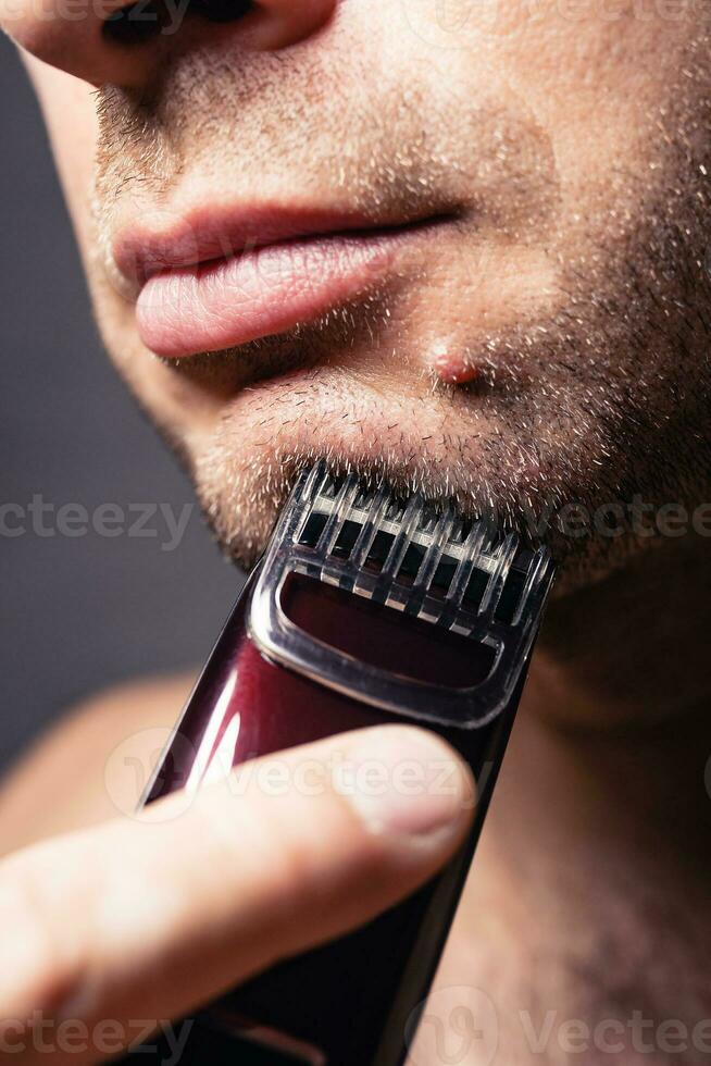 elektrisk rakapparat med en munstycke - skärande en borst på de haka av en man foto