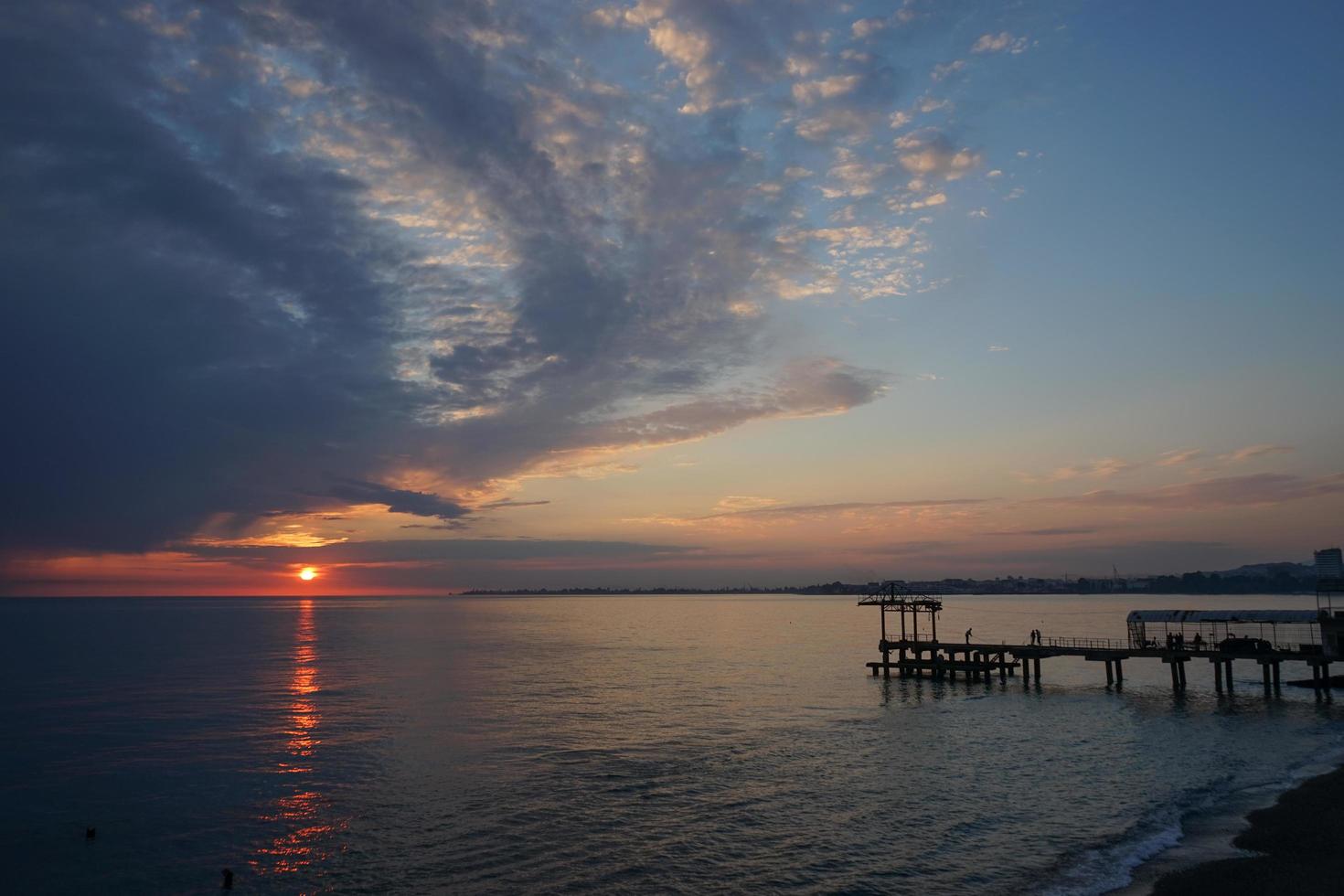 dramatisk solnedgång med mörka moln över det lugna havet foto